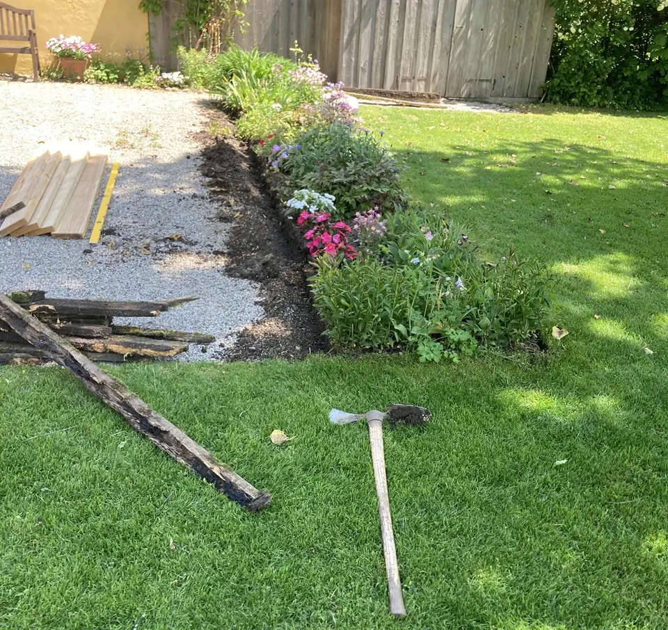 Frisch angelegtes Blumenbeet neben einem gepflegten Rasen